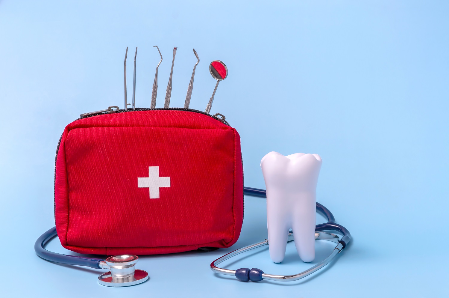 a model of a tooth, a stethoscope, a dentist's tool, a first aid kit. concept first aid for toothache